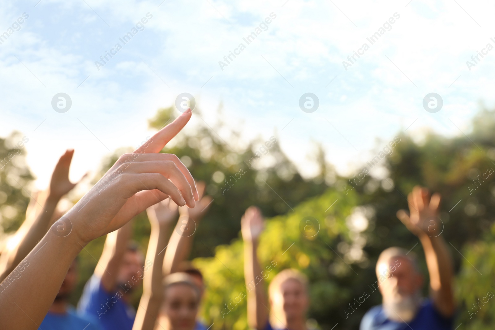 Photo of Woman at volunteers meeting, focus on hand. Group of people outdoors