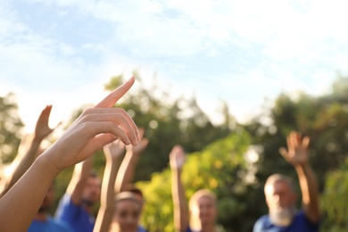 Woman at volunteers meeting, focus on hand. Group of people outdoors