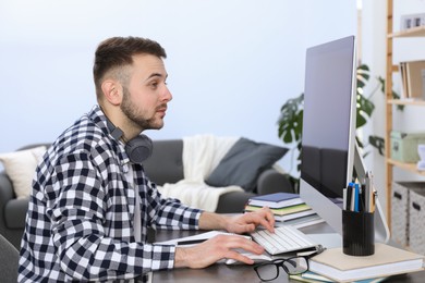 Photo of Young man using modern computer for studying at home. Distance learning