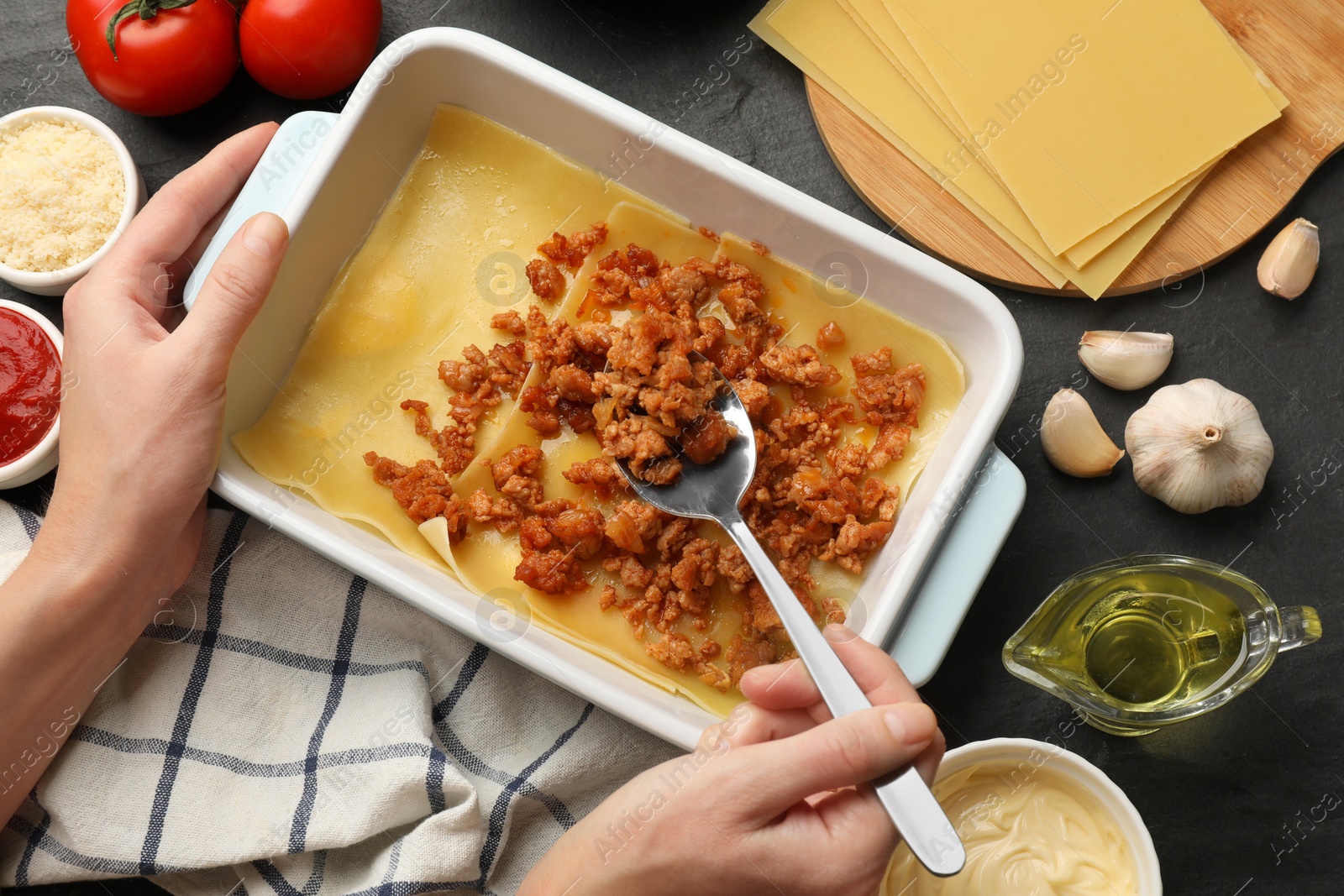 Photo of Woman making lasagna at dark table, top view