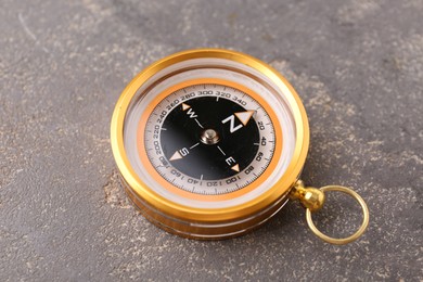 One compass on grey textured background, closeup. Navigation equipment