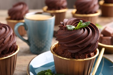 Delicious chocolate cupcakes with mint on table, closeup