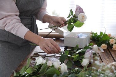 Photo of Florist making beautiful wedding bouquet at wooden table, closeup