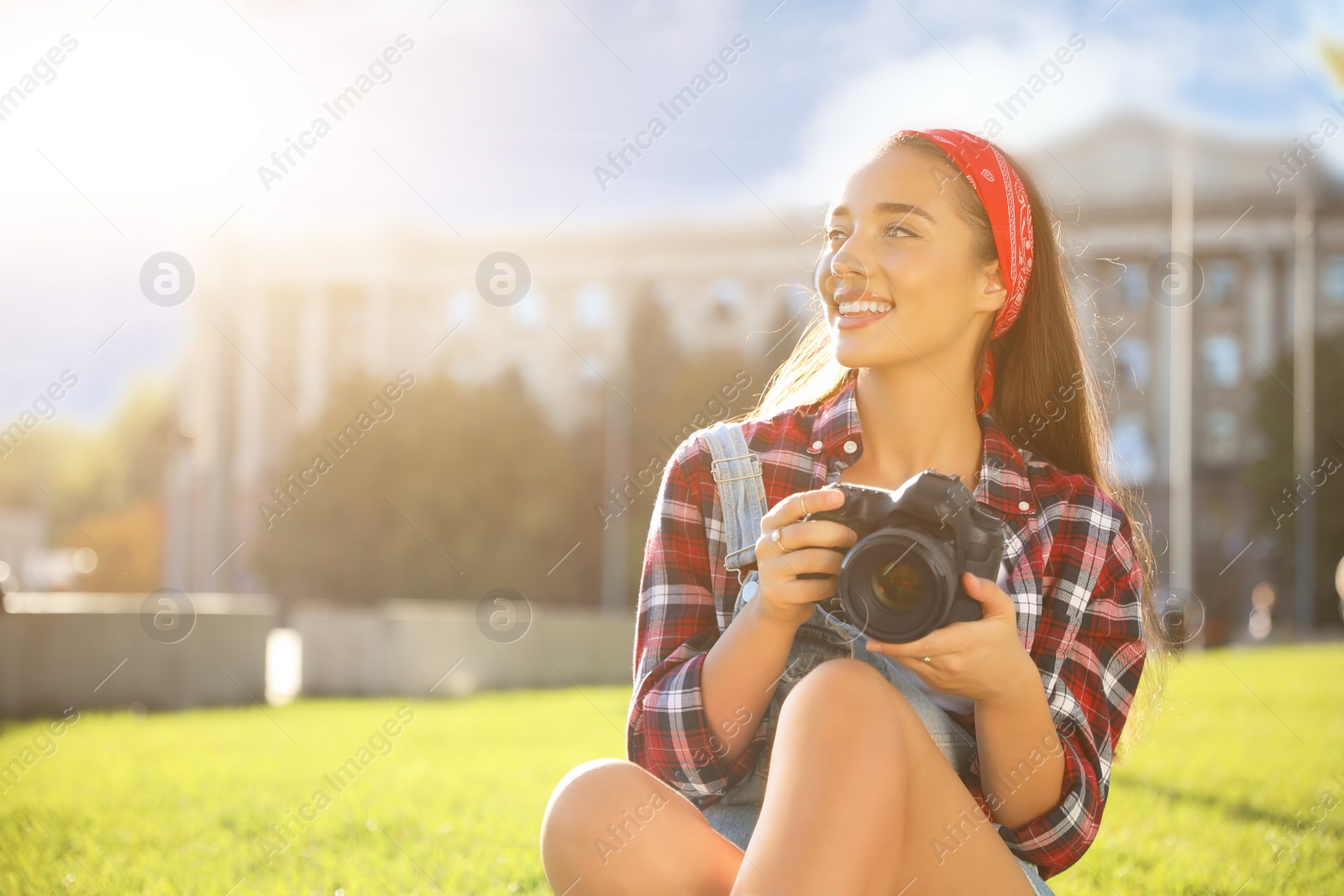 Photo of Young photographer with professional camera on green grass outdoors. Space for text