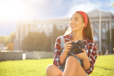 Photo of Young photographer with professional camera on green grass outdoors. Space for text