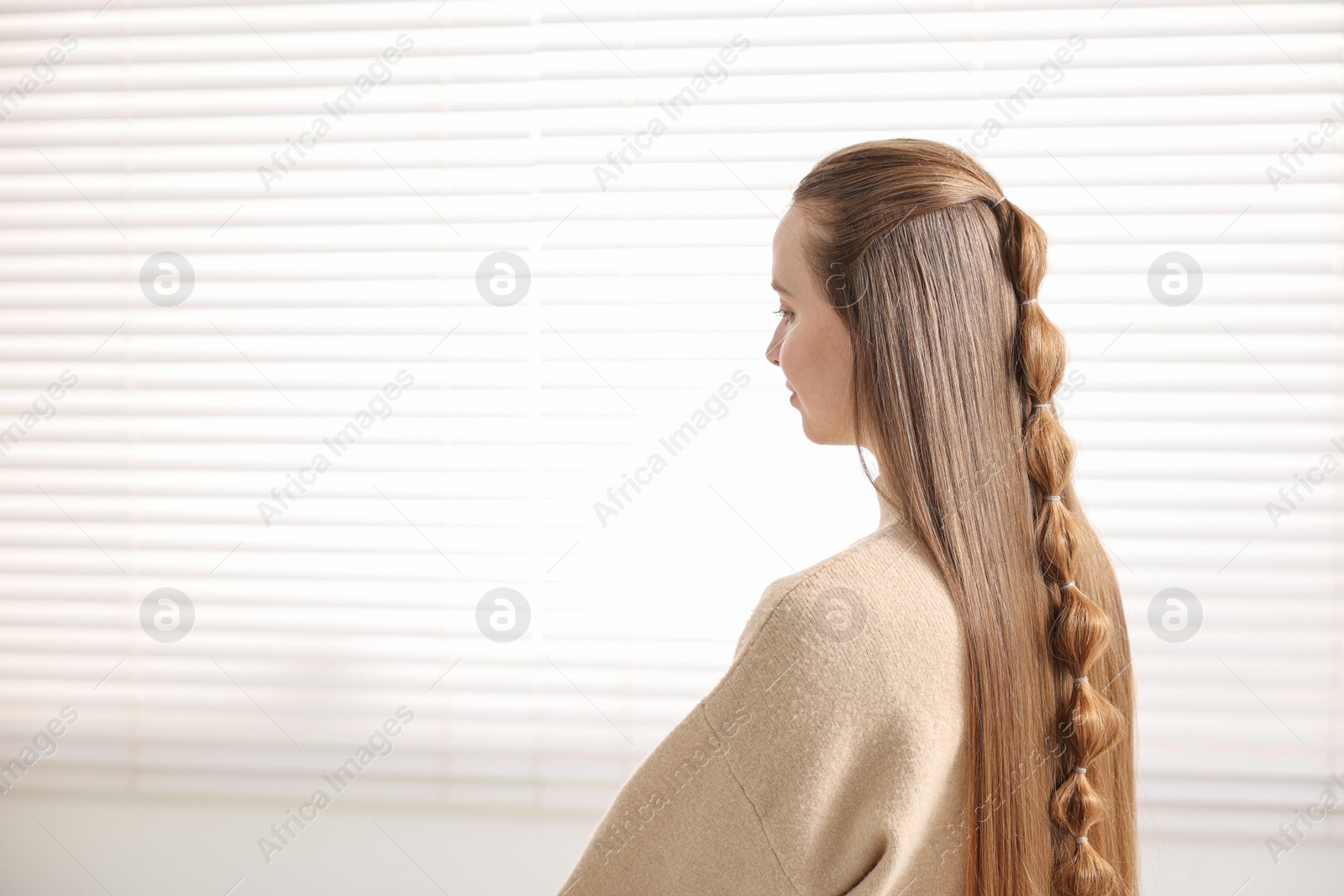 Photo of Young woman with long braided hair indoors, space for text