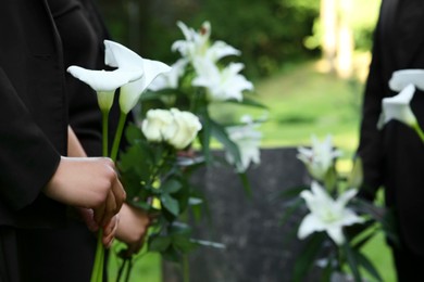 People with flowers outdoors, closeup and space for text. Funeral ceremony