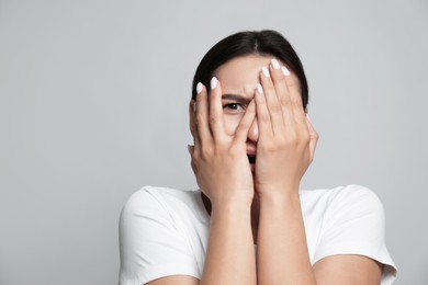 Young woman feeling fear on grey background