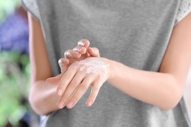 Young woman applying cream on her hands, closeup