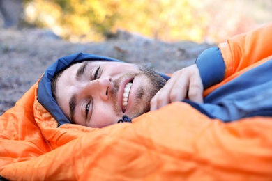 Photo of Male camper lying in sleeping bag on ground