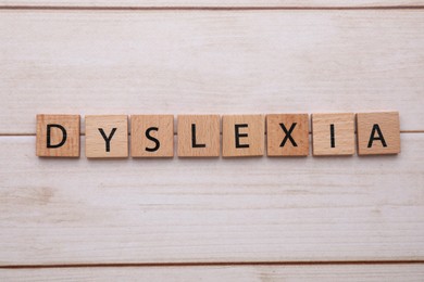 Photo of Tiles with word Dyslexia on wooden table, flat lay