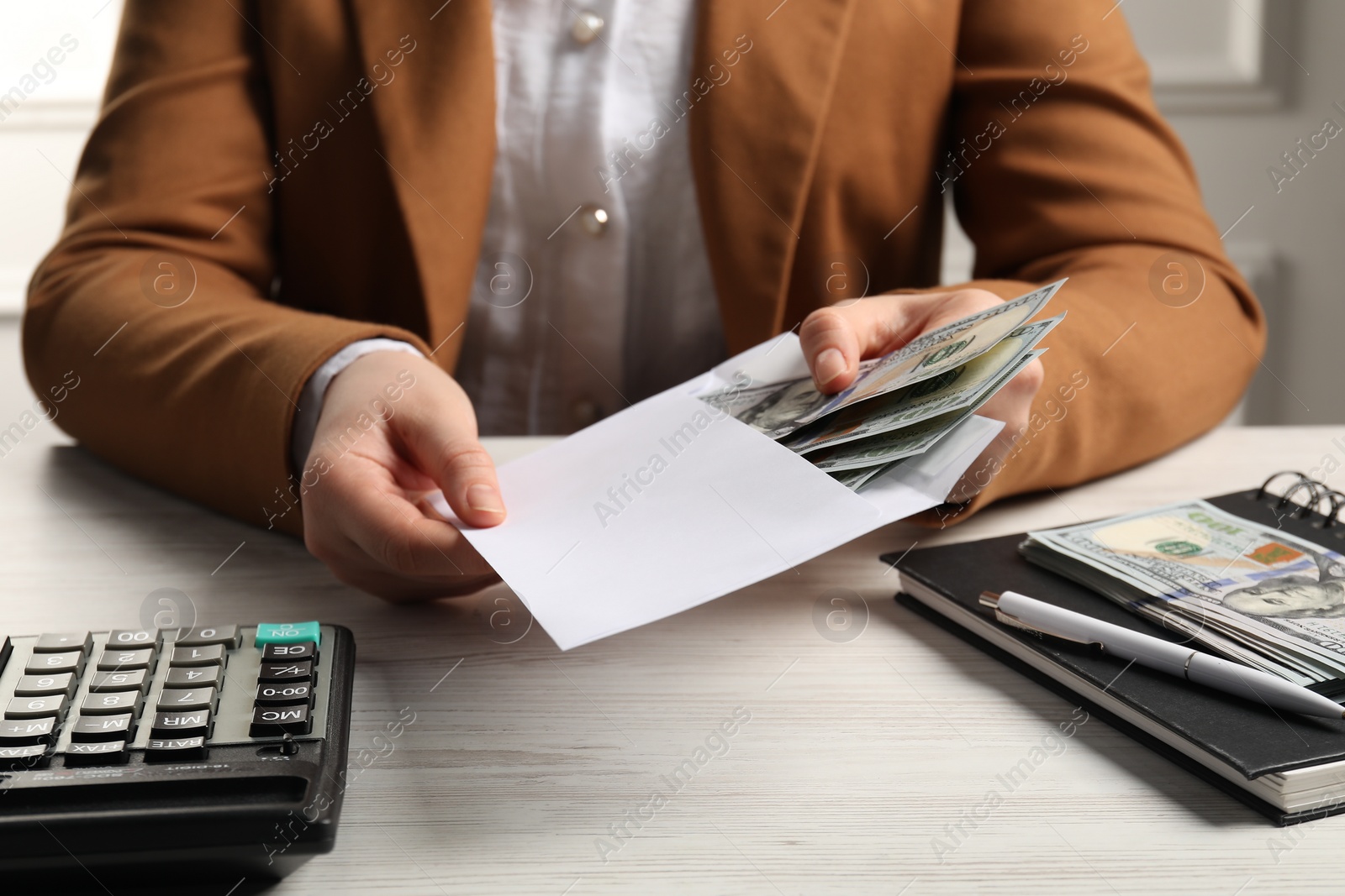 Photo of Money exchange. Woman holding dollar banknotes at white wooden table, closeup