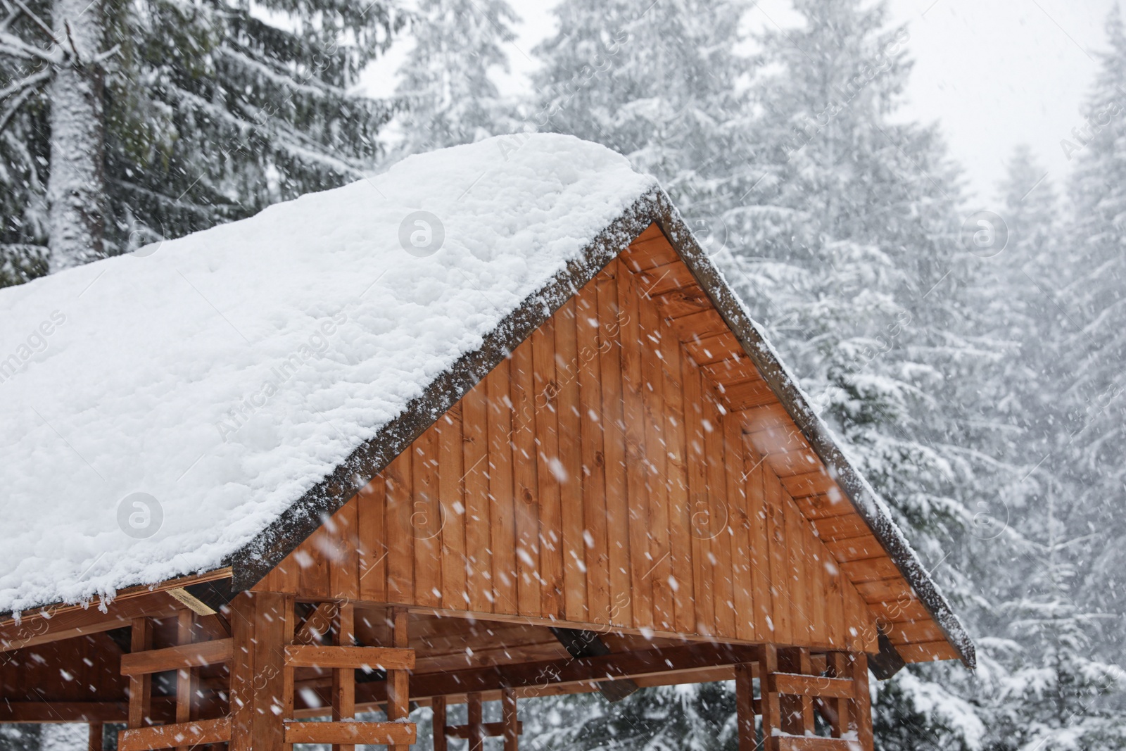 Photo of Modern wooden gazebo on snowy day. Winter vacation