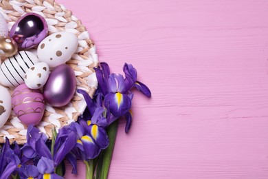 Photo of Flat lay composition with festively decorated Easter eggs and iris flowers on pink wooden background. Space for text