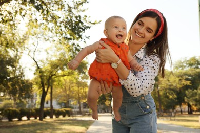 Young mother with her cute baby in park on sunny day