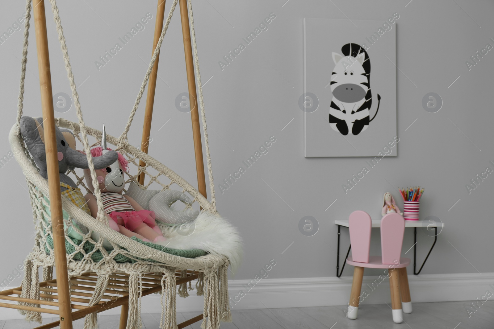 Photo of Stylish child's room interior with adorable painting and hanging chair