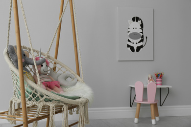 Photo of Stylish child's room interior with adorable painting and hanging chair