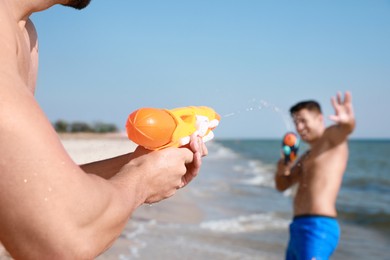 Photo of Friends with water guns having fun on beach