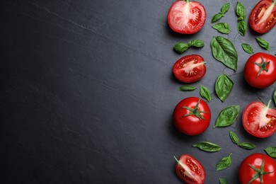 Fresh basil leaves and tomatoes on black slate table, flat lay. Space for text