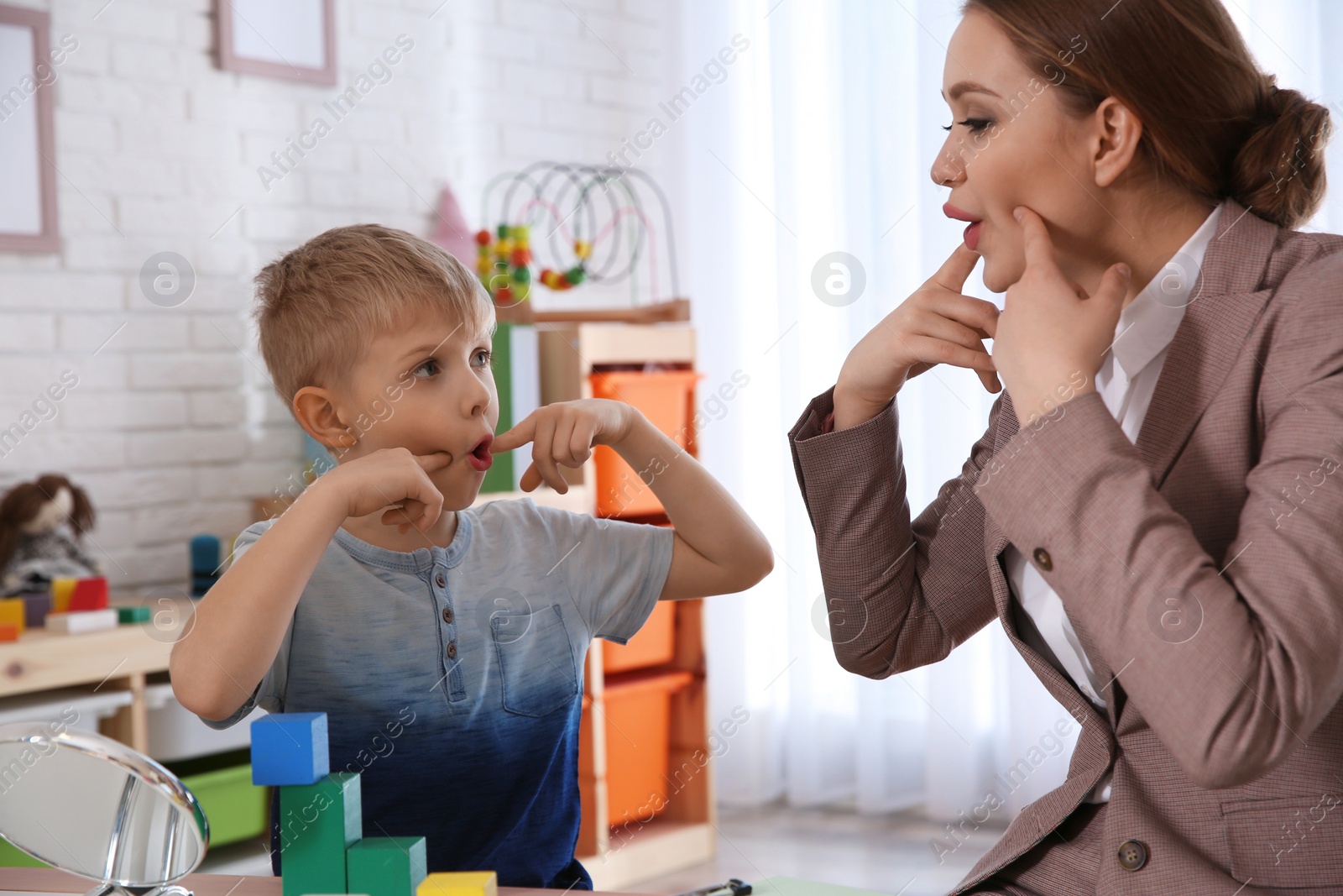 Photo of Speech therapist working with little boy in office