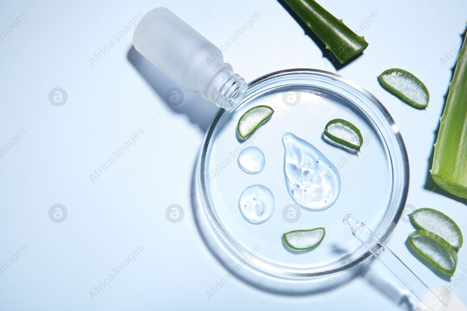 Photo of Cut aloe vera, bottle and drops of cosmetic gel on light blue background, flat lay. Space for text