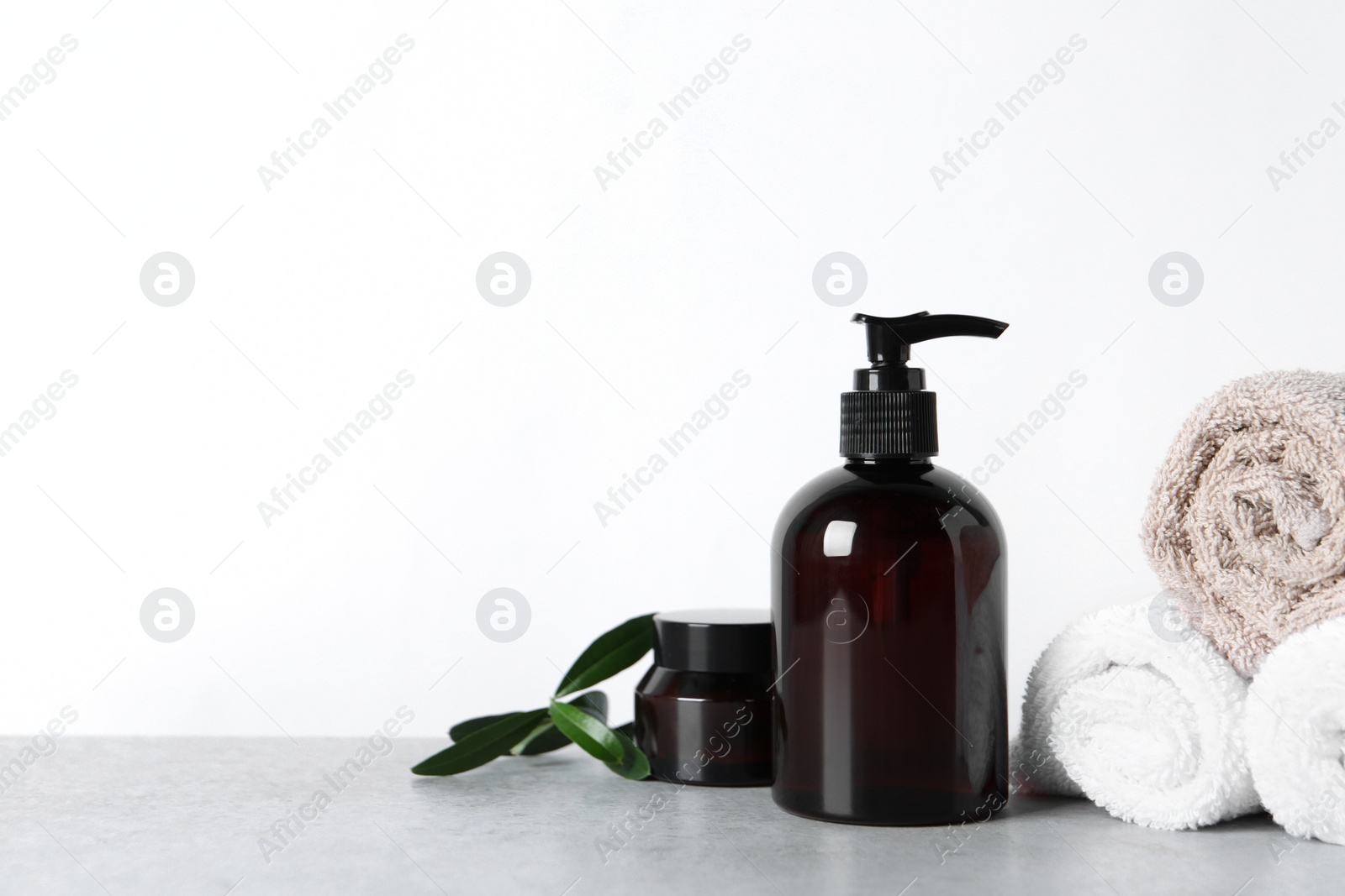 Photo of Cosmetic products and towels on light grey table, space for text