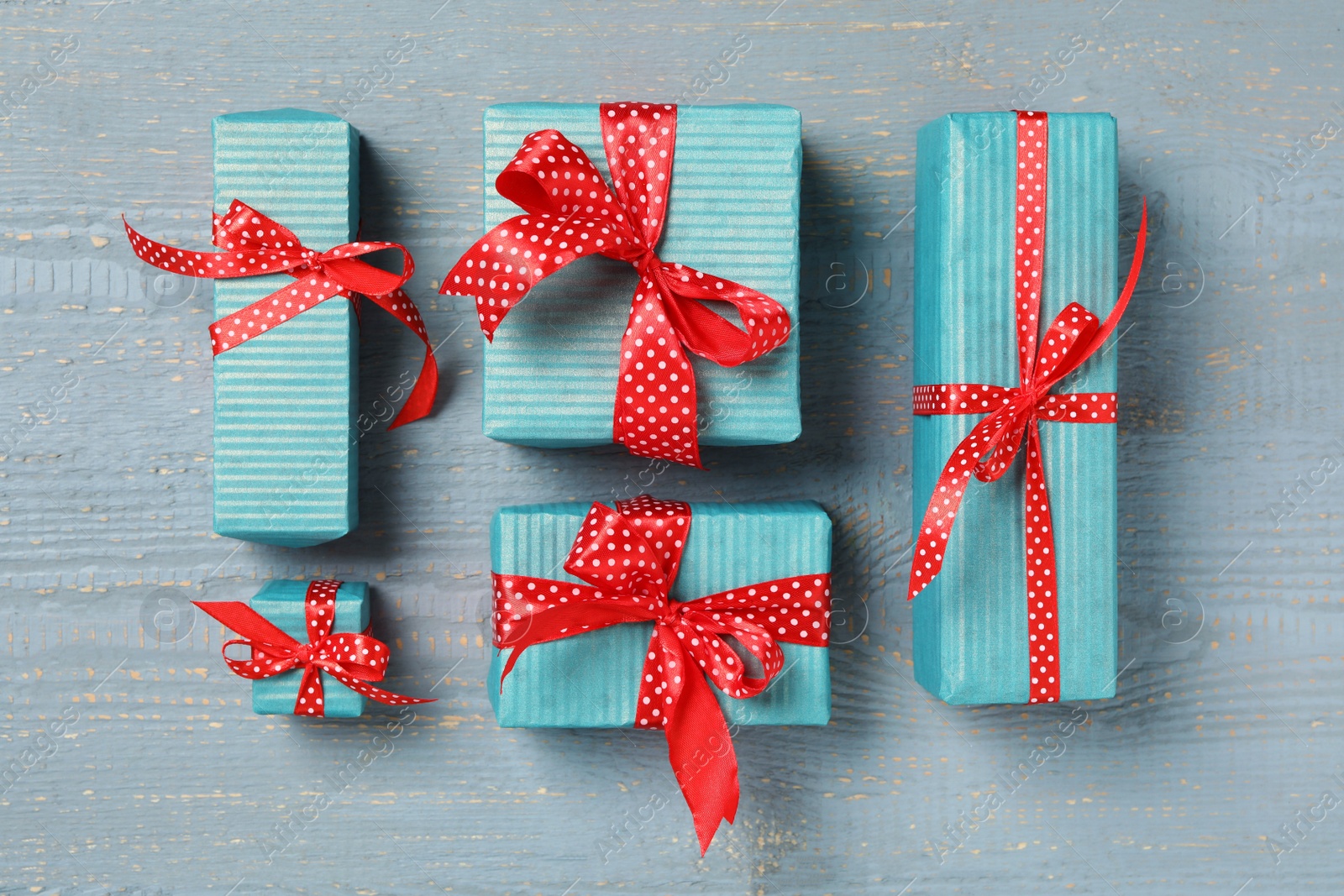 Photo of Christmas gift boxes with red bows on grey wooden background, flat lay