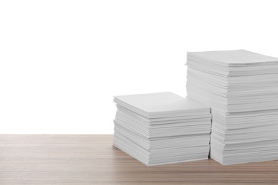 Stacks of paper sheets on wooden table against white background. Space for text