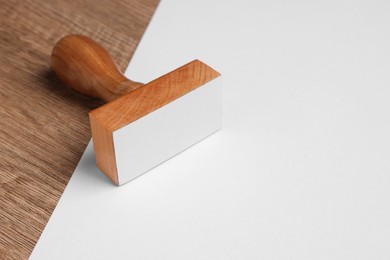 Photo of One stamp tool and sheet of paper on wooden table, closeup. Space for text