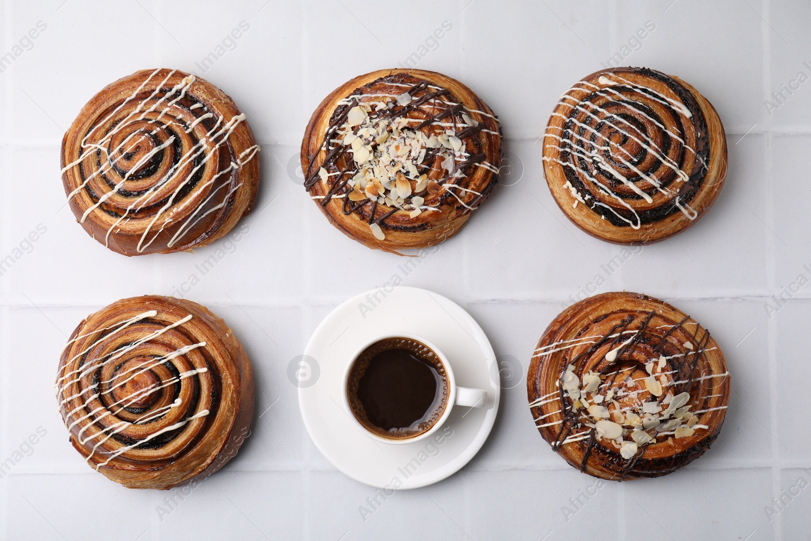 Photo of Delicious rolls with nuts, toppings and coffee cup on white tiled table, flat lay. Sweet buns