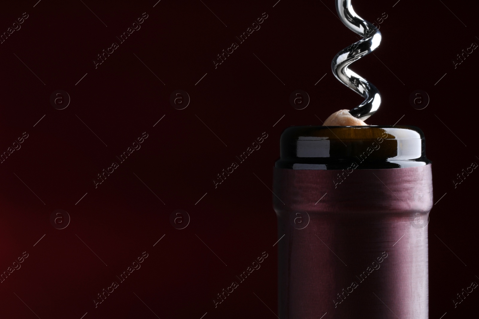 Photo of Opening bottle of wine with corkscrew on dark background, closeup. Space for text