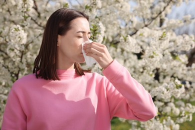 Woman with napkin suffering from seasonal allergy on spring day