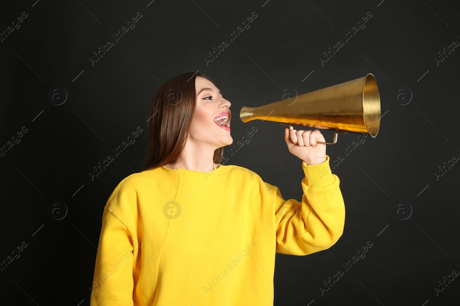 Photo of Young woman with megaphone on black background