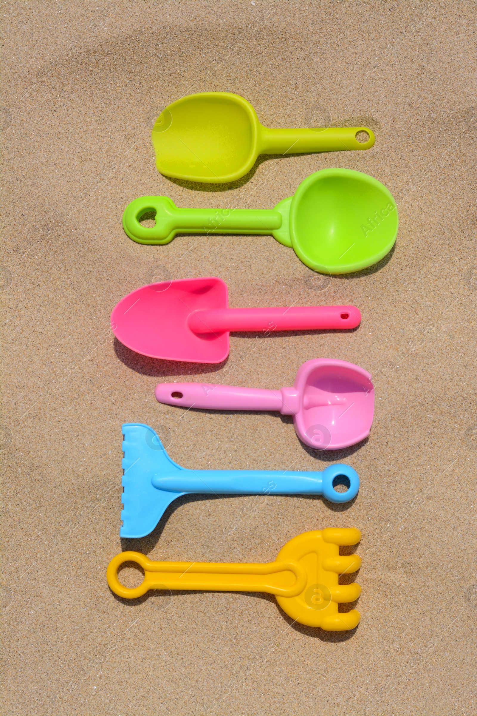 Photo of Set of colorful beach toys on sand, flat lay