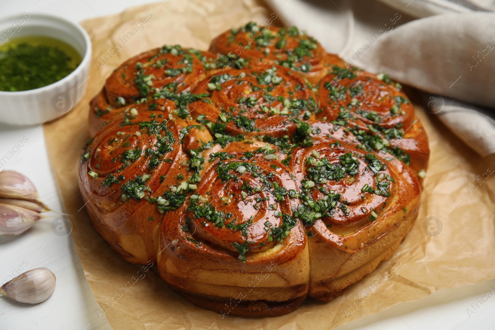 Photo of Traditional Ukrainian garlic bread with herbs (Pampushky) on white wooden table, closeup