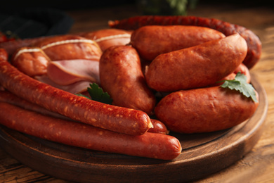 Different tasty sausages on wooden table, closeup