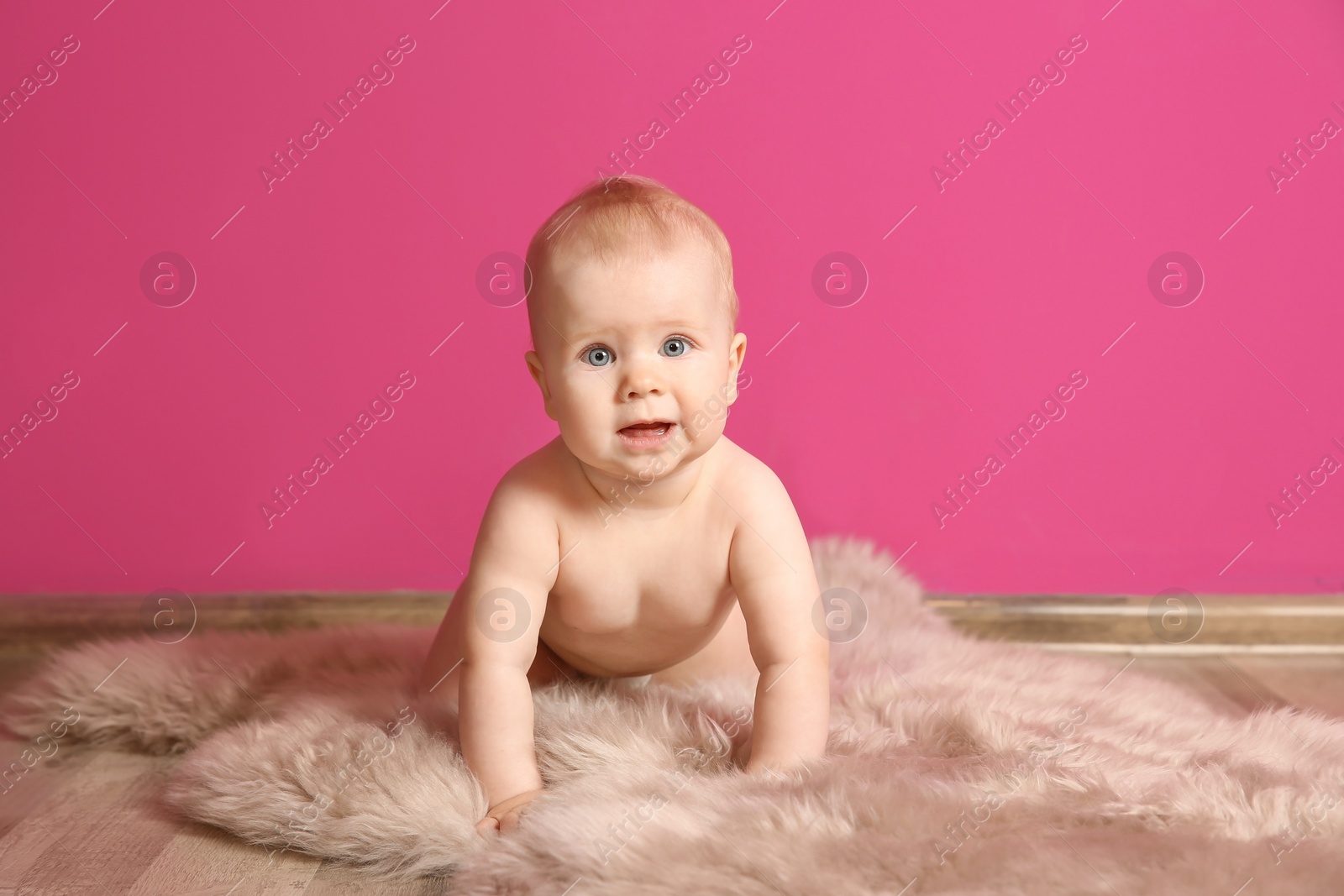 Photo of Cute little baby on fluffy rug near color wall