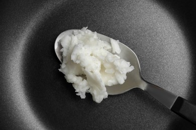 Frying pan with coconut oil and spoon, closeup