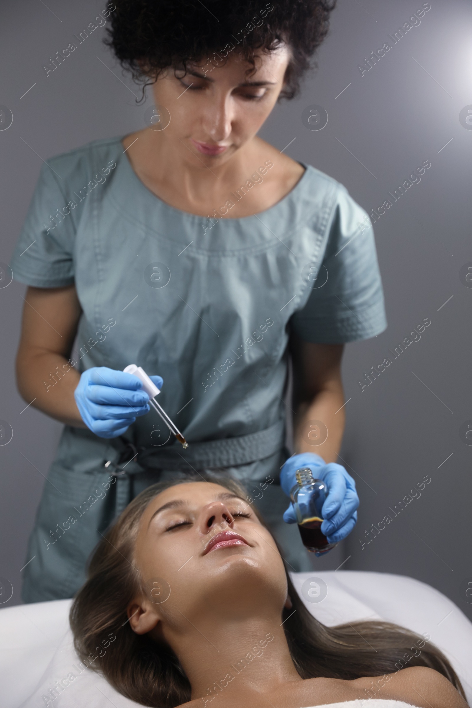 Photo of Cosmetologist applying serum on client's face in salon