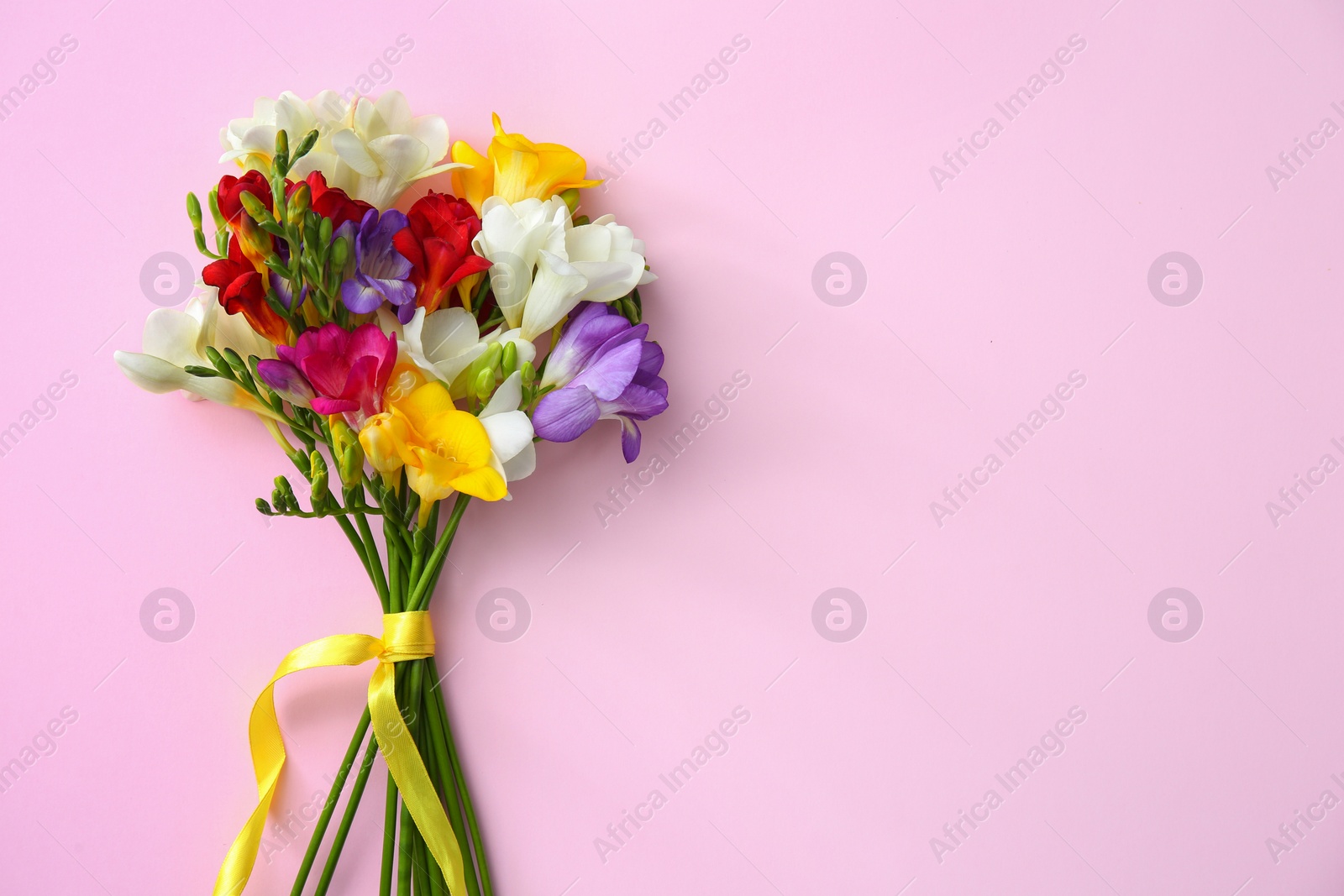 Photo of Beautiful freesia bouquet with ribbon on color background