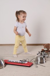 Cute little girl with cookware and toy piano at home