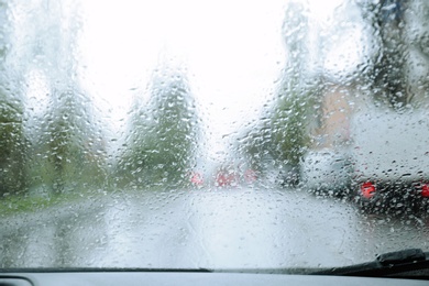 Blurred view of road through wet car window. Rainy weather