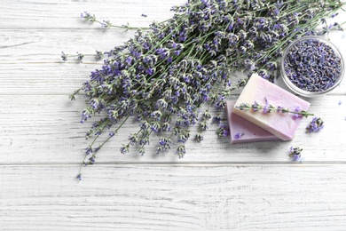 Photo of Flat lay composition of handmade soap bars with lavender flowers on white wooden background. space for text