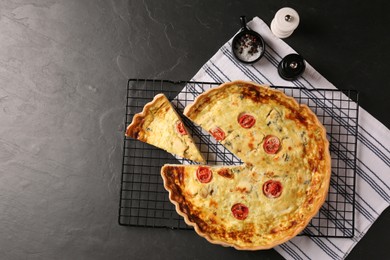 Photo of Delicious homemade cheese quiche and spices on black table, flat lay