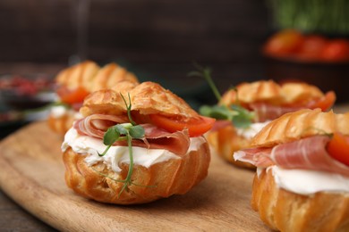 Photo of Delicious profiteroles with cream cheese, jamon and tomato on table, closeup