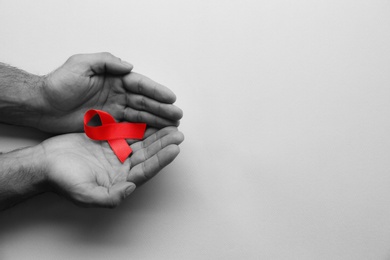 Image of World AIDS disease day. Man holding red awareness ribbon on white background, top view with space for text 