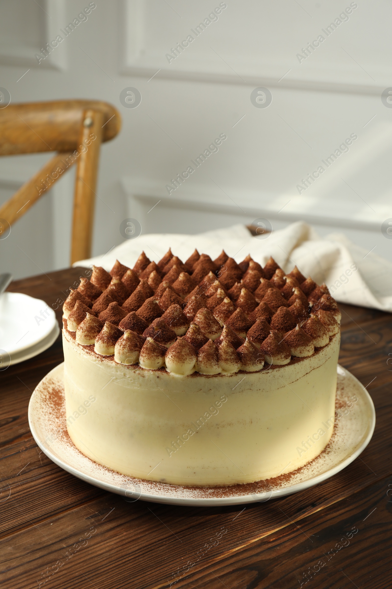 Photo of Delicious tiramisu cake with cocoa powder on wooden table, space for text