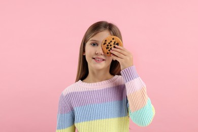 Photo of Cute girl with chocolate chip cookie on pink background