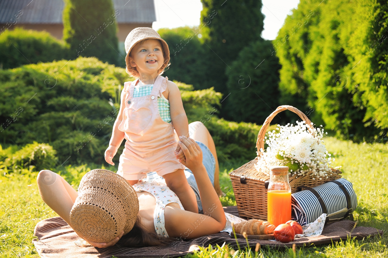 Photo of Mother with her baby daughter resting while having picnic in garden on sunny day