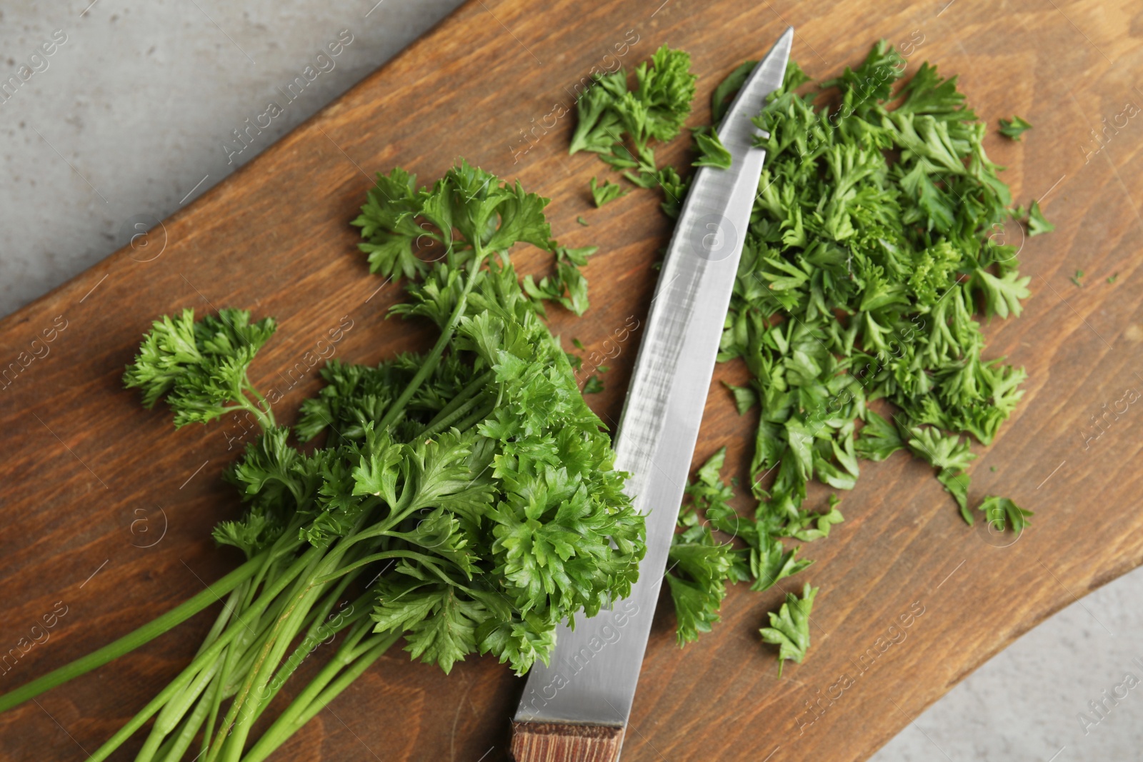 Photo of Wooden board with fresh green parsley and knife on table, top view